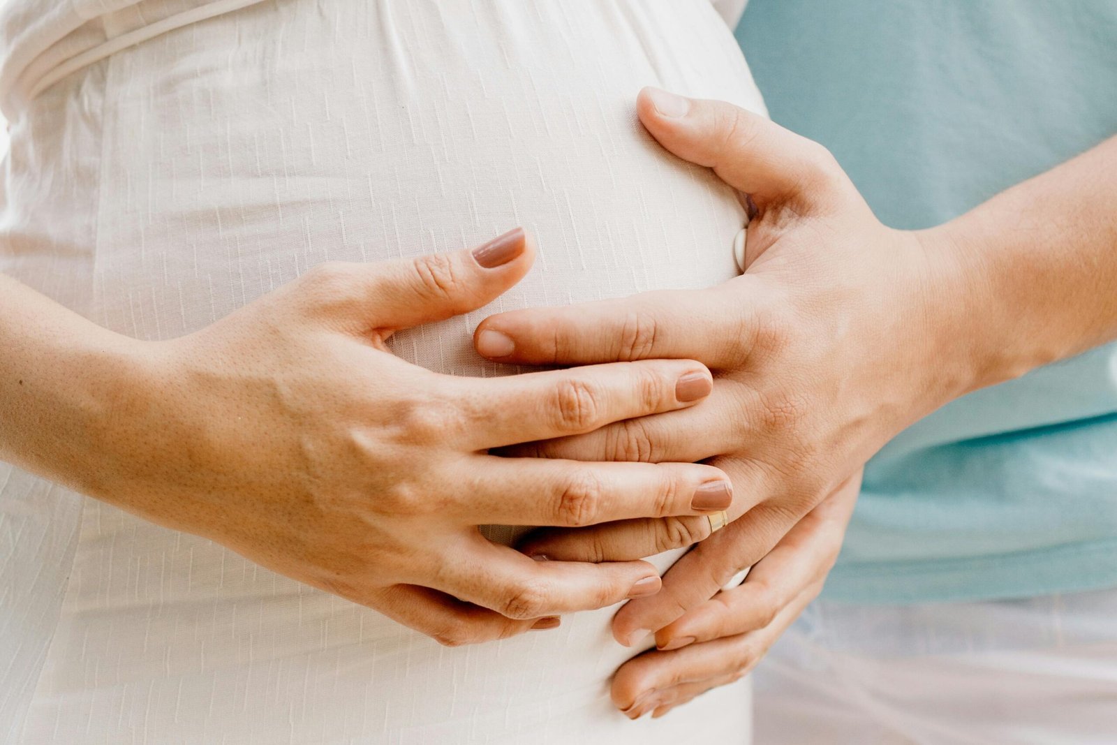 Close-up of hands gently embracing a baby bump in a warm, serene setting.